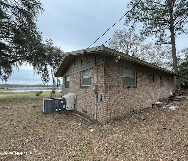 view of side of home with cooling unit and brick siding