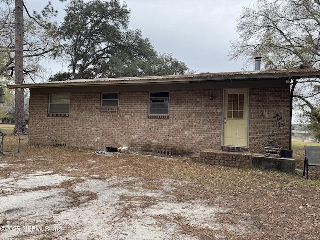 rear view of property with brick siding and crawl space