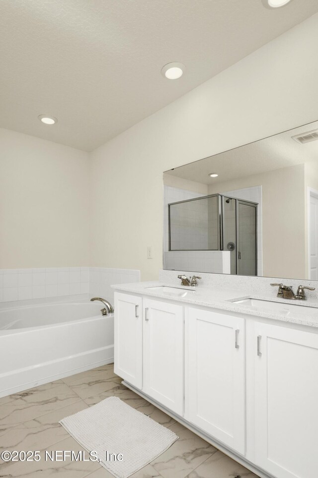 full bathroom with double vanity, marble finish floor, a garden tub, and a sink