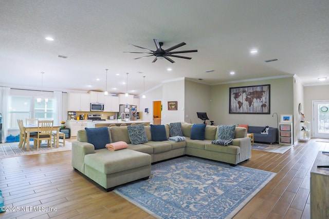 living room featuring visible vents, wood finished floors, and crown molding