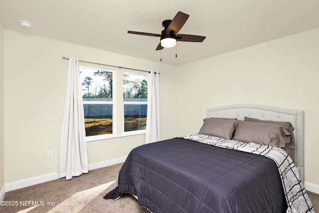 carpeted bedroom with ceiling fan, a textured ceiling, and baseboards