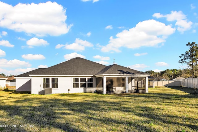 rear view of property with a lawn, fence, a sunroom, and a shingled roof