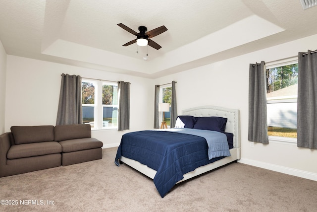 carpeted bedroom with visible vents, a raised ceiling, a textured ceiling, baseboards, and ceiling fan