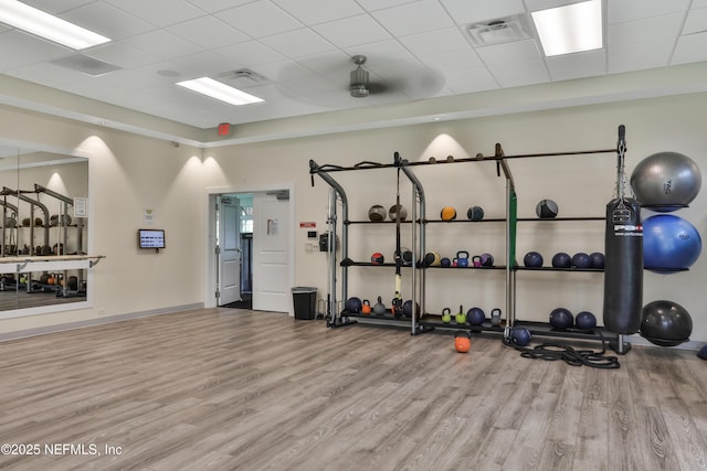 gym with visible vents, a paneled ceiling, baseboards, and wood finished floors