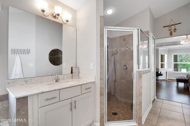 bathroom with tile patterned flooring, vaulted ceiling, vanity, and a stall shower