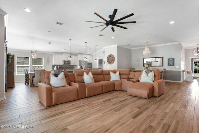 living room with visible vents, recessed lighting, crown molding, ceiling fan with notable chandelier, and light wood-type flooring