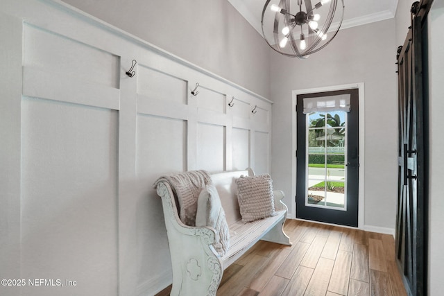 mudroom featuring ornamental molding, wood finished floors, a barn door, baseboards, and a chandelier