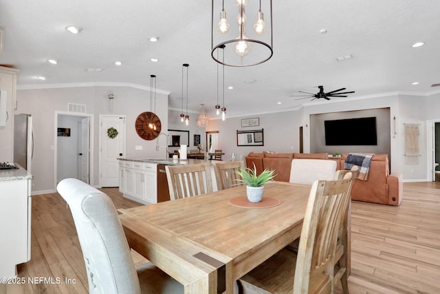 dining room featuring visible vents, light wood-type flooring, and ornamental molding