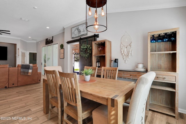 dining room with recessed lighting, crown molding, light wood-type flooring, and a barn door