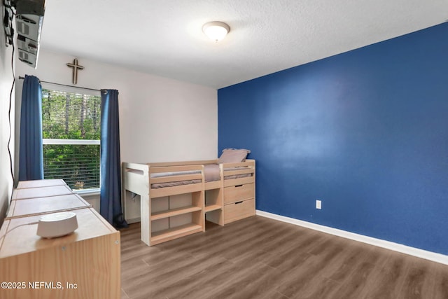 unfurnished bedroom with wood finished floors, baseboards, and a textured ceiling