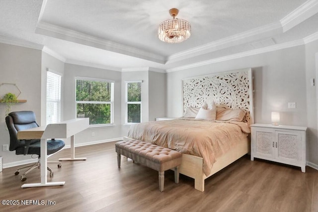 bedroom with crown molding, a raised ceiling, baseboards, and wood finished floors