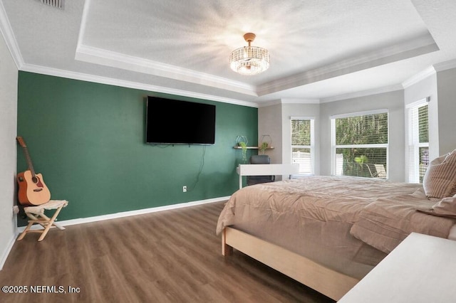 bedroom featuring a tray ceiling, baseboards, wood finished floors, and a chandelier