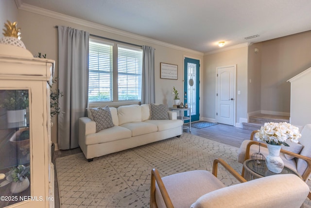 living room featuring visible vents, light wood-type flooring, baseboards, and ornamental molding