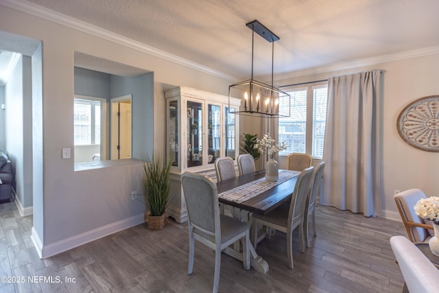 dining space with a notable chandelier, plenty of natural light, ornamental molding, and wood finished floors