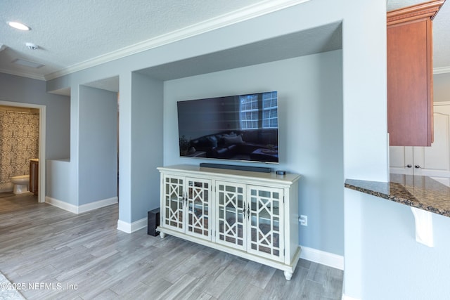 living area featuring crown molding, wood finished floors, baseboards, and a textured ceiling