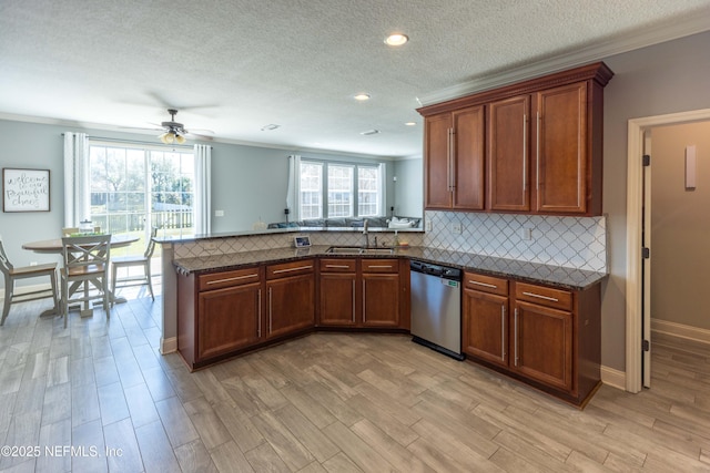 kitchen with backsplash, a peninsula, stainless steel dishwasher, a ceiling fan, and a sink