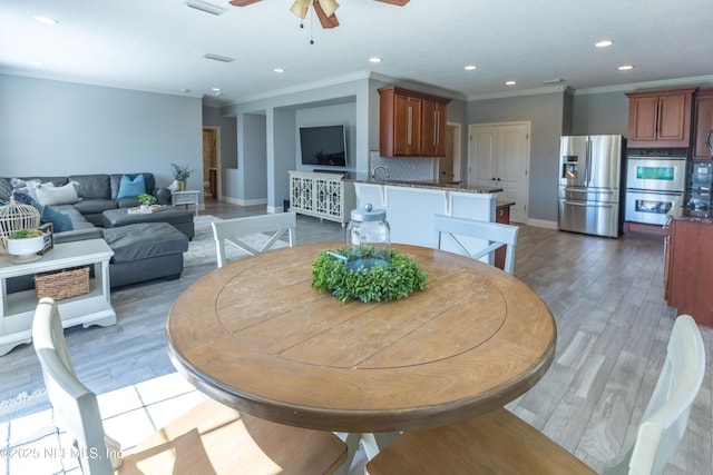 dining space with light wood-type flooring, ornamental molding, recessed lighting, baseboards, and ceiling fan