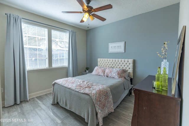 bedroom with a textured ceiling, wood finished floors, baseboards, and ceiling fan