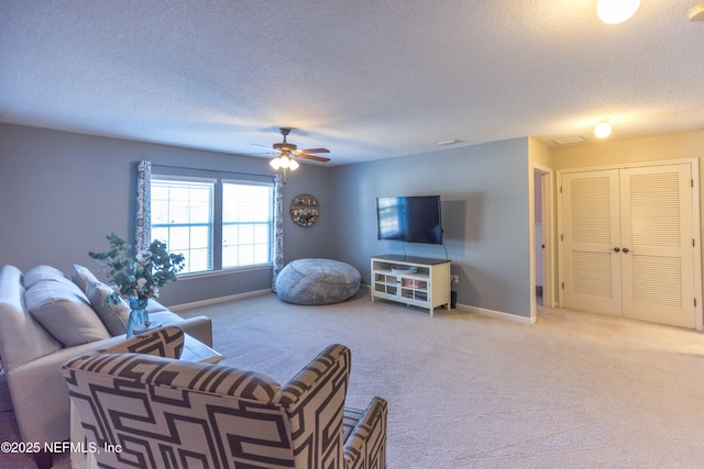 carpeted living area with baseboards, a textured ceiling, and ceiling fan