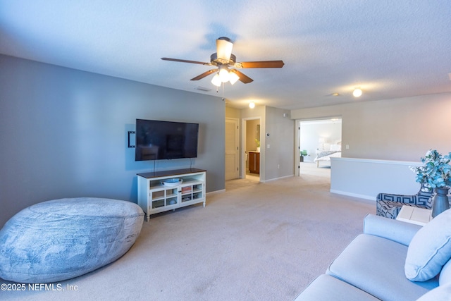 living area featuring visible vents, baseboards, carpet flooring, a textured ceiling, and a ceiling fan