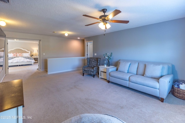 living area with baseboards, carpet flooring, a textured ceiling, and ceiling fan