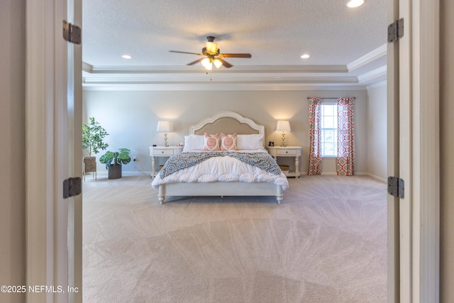 carpeted bedroom featuring baseboards, a textured ceiling, a tray ceiling, and ornamental molding