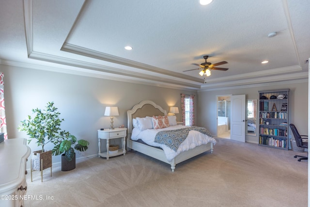 bedroom featuring baseboards, a tray ceiling, ornamental molding, light colored carpet, and connected bathroom