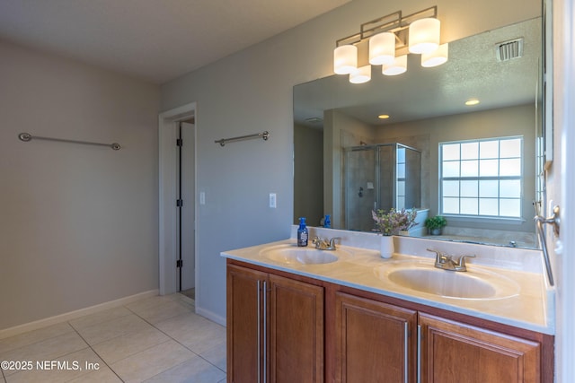 bathroom featuring tile patterned floors, visible vents, a stall shower, and a sink