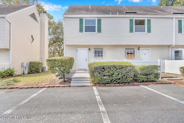 multi unit property featuring uncovered parking, a shingled roof, and fence