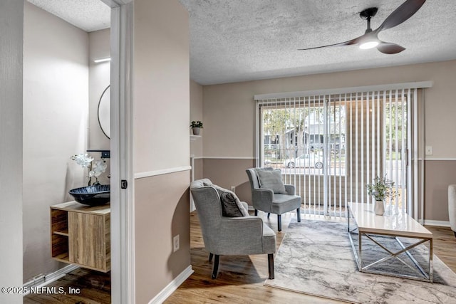 sitting room featuring a healthy amount of sunlight, a textured ceiling, a ceiling fan, and wood finished floors