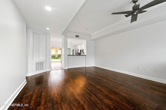 unfurnished living room with visible vents, ornamental molding, dark wood finished floors, baseboards, and ceiling fan