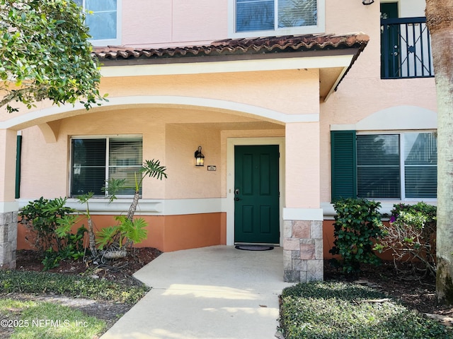 entrance to property featuring stucco siding and a tiled roof