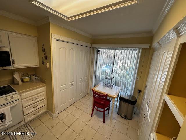 interior space with ornamental molding, white range with electric stovetop, white cabinets, light countertops, and light tile patterned floors