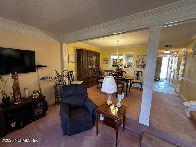 living area with visible vents, carpet, a chandelier, ornamental molding, and ornate columns