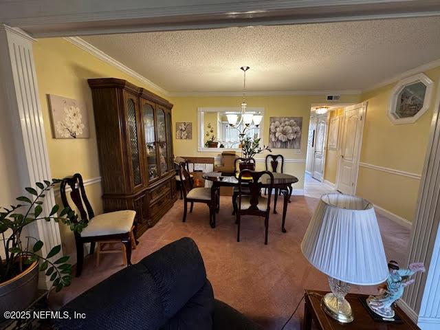 dining space featuring carpet flooring, a notable chandelier, ornamental molding, and a textured ceiling