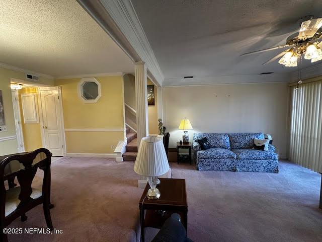 living room featuring stairway, a textured ceiling, crown molding, and carpet floors