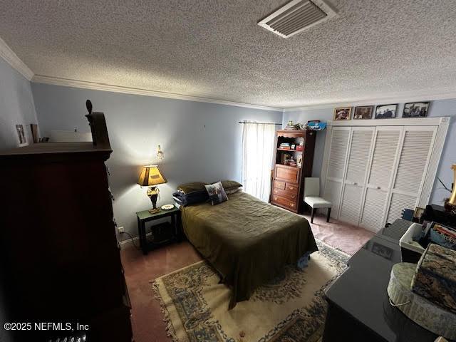 bedroom with visible vents, a textured ceiling, and crown molding