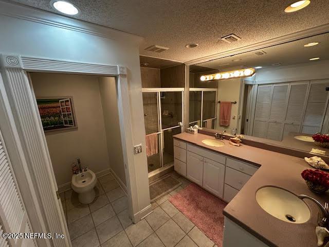 bathroom with vanity, a bidet, a stall shower, tile patterned flooring, and a textured ceiling