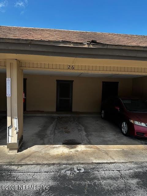 exterior space featuring covered parking and a shingled roof