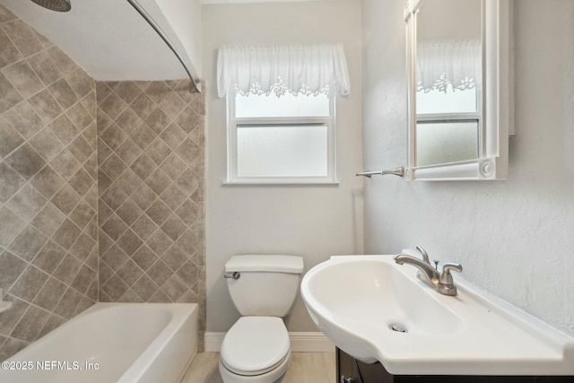 bathroom featuring vanity, toilet, baseboards, and shower / washtub combination