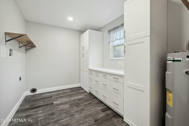 clothes washing area with dark wood finished floors, baseboards, hookup for an electric dryer, and electric water heater