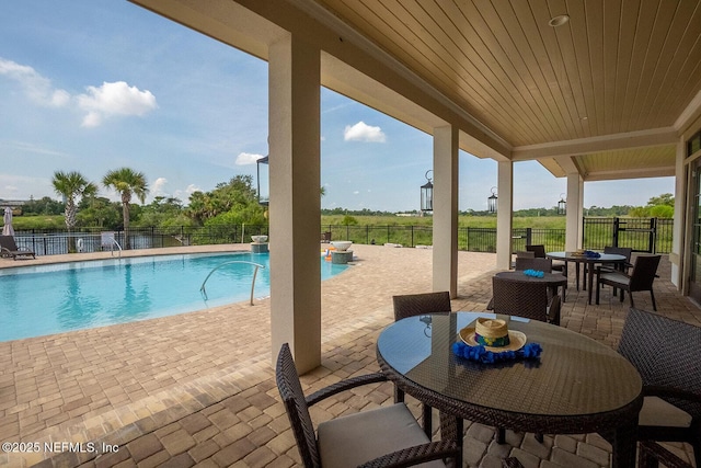 community pool featuring a patio area, outdoor dining area, and fence