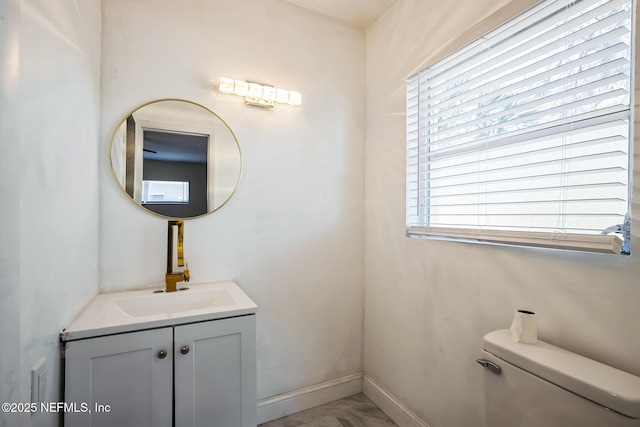 bathroom with toilet, vanity, and baseboards