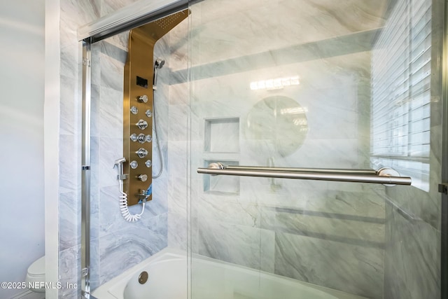 bathroom with toilet and bath / shower combo with glass door