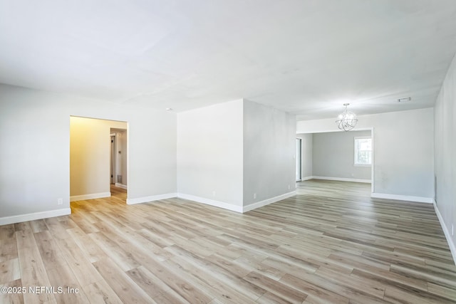 unfurnished room featuring visible vents, baseboards, an inviting chandelier, and light wood-style flooring