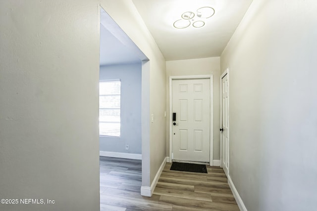 doorway featuring baseboards and wood finished floors