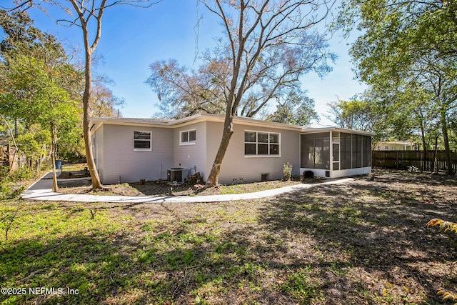 rear view of property with central air condition unit, fence, a yard, and a sunroom