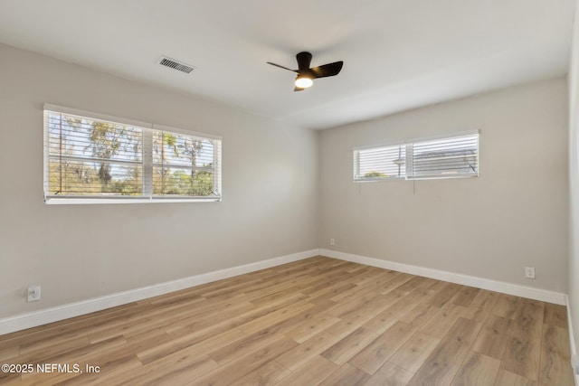 empty room with a ceiling fan, light wood-style flooring, baseboards, and visible vents