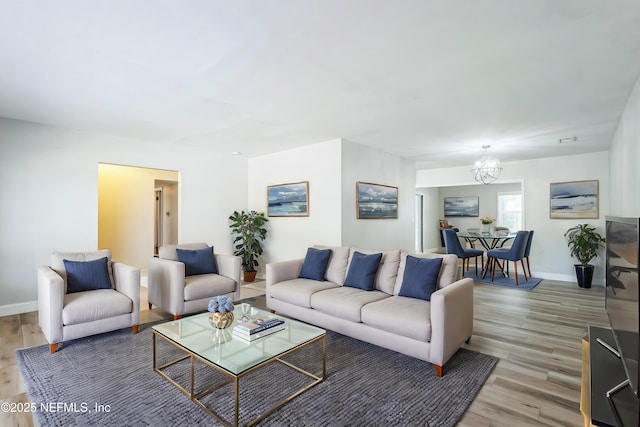 living room featuring a chandelier, light wood-type flooring, and baseboards