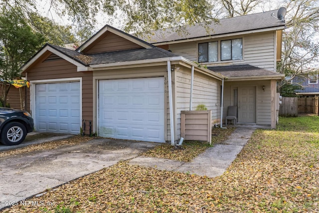 view of front of home with concrete driveway, a shingled roof, a garage, and fence